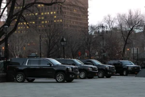 black suvs with chauffeurs lined up infront of private schools in new york